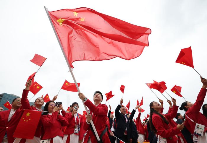 7月26日，中国体育代表团旗手、乒乓球选手马龙在开幕式前挥舞国旗。
