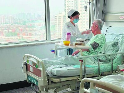     在天津市第三中心医院“无陪伴”病房，护士李东晶正为患者喂餐。   中国妇女报全媒体记者 高丽/摄