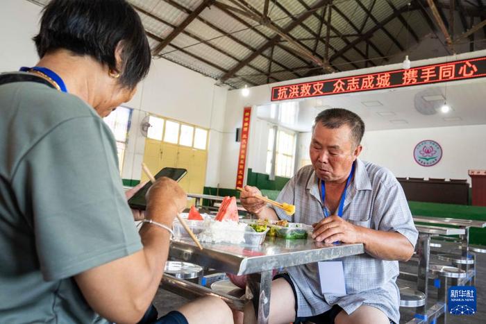   7月30日，转移安置的群众在湘潭县河口中学安置点吃午餐。新华社记者 陈思汗 摄