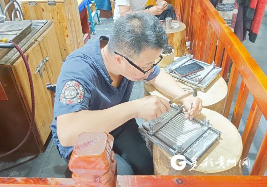 西江千户苗寨景区内，商户在制作银饰产品