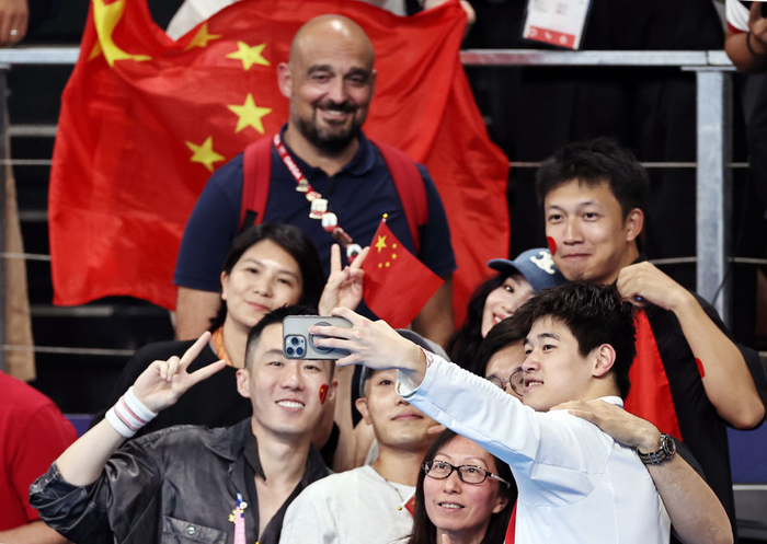 ↑中国选手潘展乐（右一）在颁奖仪式后与观众合影。新华社记者 雒圆 摄