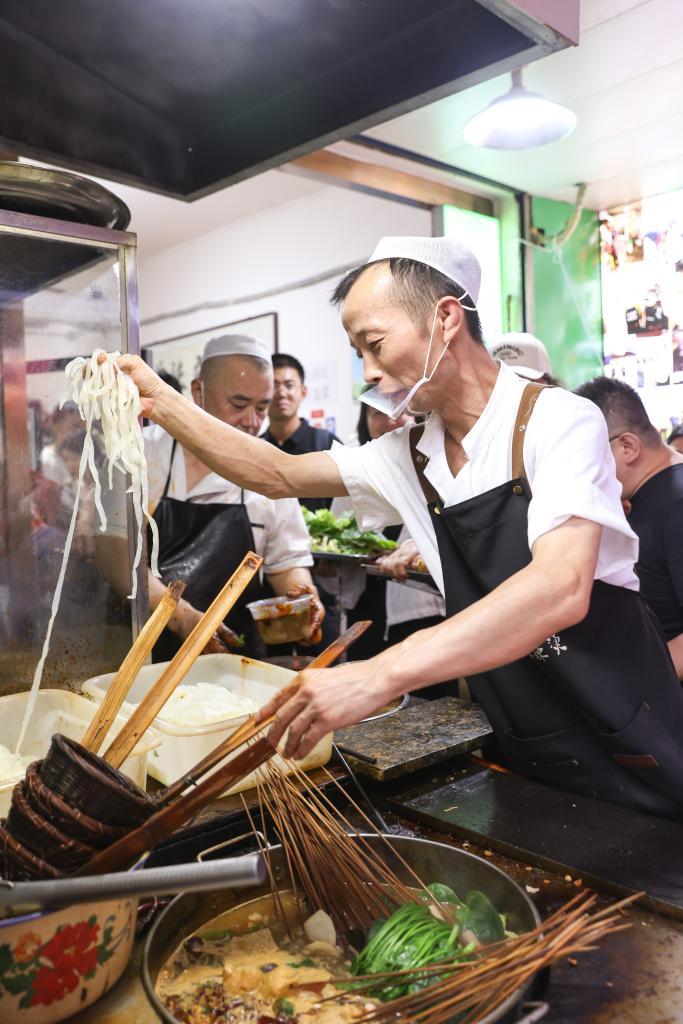   7月22日，工作人员在甘肃天水市名优小吃城的一家店铺制作麻辣烫。新华社记者 吕帅 摄