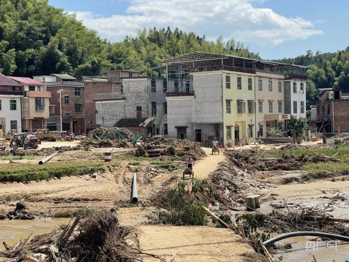 △距离抢修现场不远处当地村民自发进行道路填土工作（记者江晓晨 摄）