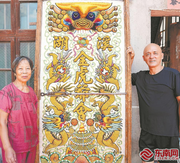浦东锦绣庄经营者吴明华与妻子在绣品前合影。