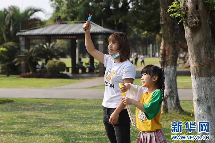 家长带着孩子在海口万绿园放风筝,享受健康生活.新华网发
