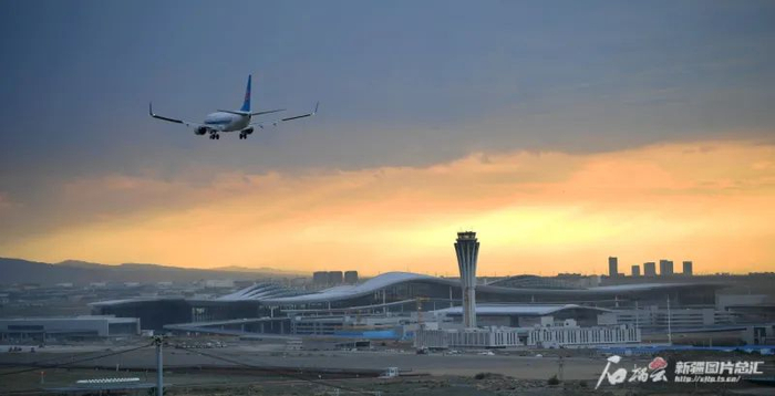 一架客机飞过乌鲁木齐机场改扩建工程T4航站楼上方（资料图片）。石榴云/新疆日报记者 邹懿摄