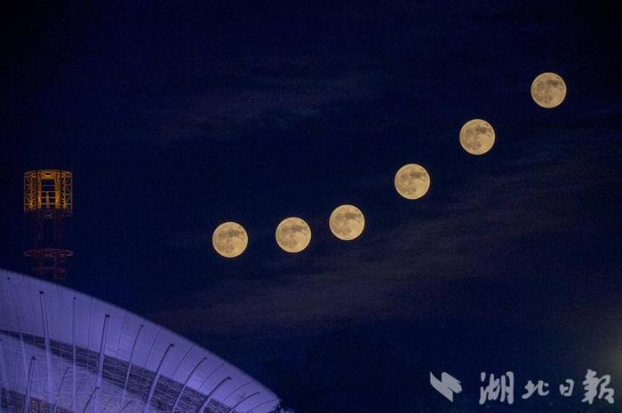 图为武汉东湖高新区未来科技城，一轮淡红色的超级月亮升起，与地标马蹄莲大楼交相辉映。（多重曝光照片）