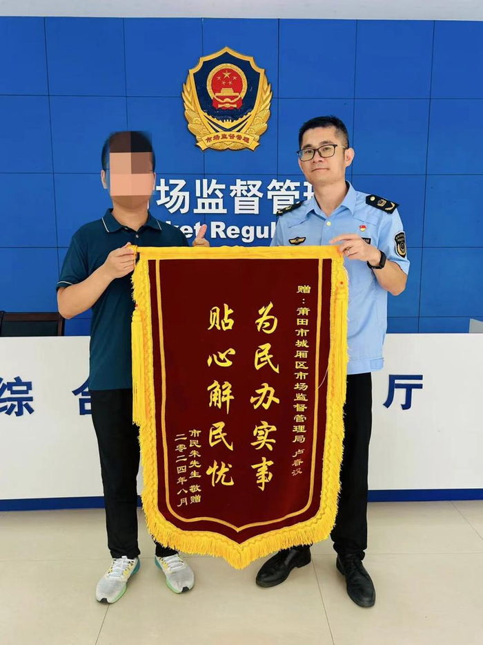 图为消费者为执法人员赠送锦旗