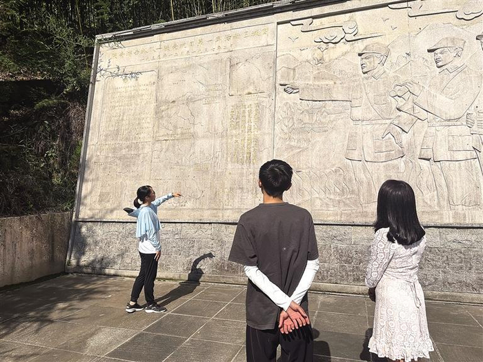 8月19日，陕南人民抗日第一军纪念碑后的浮雕墙前，讲解员向游客讲述革命故事。 记者 齐珂雨摄
