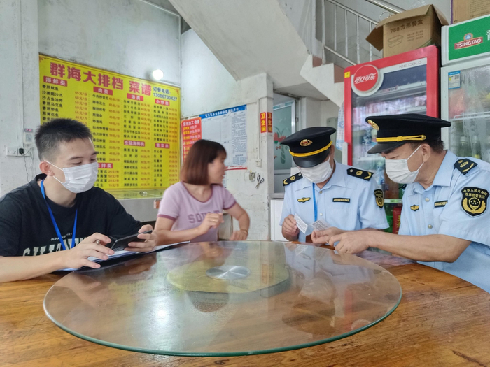 执法人员检查港口区企沙镇一家海鲜餐饮店从业人员健康证。