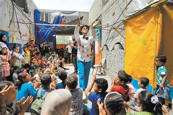 图为在加沙地带中部城市代尔拜拉赫的一所临时学校内，孩子们和志愿者互动。新华社发