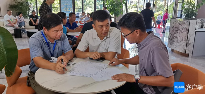 图为村民在向征收小组人员咨询征收签约相关政策。记者 王康景 摄