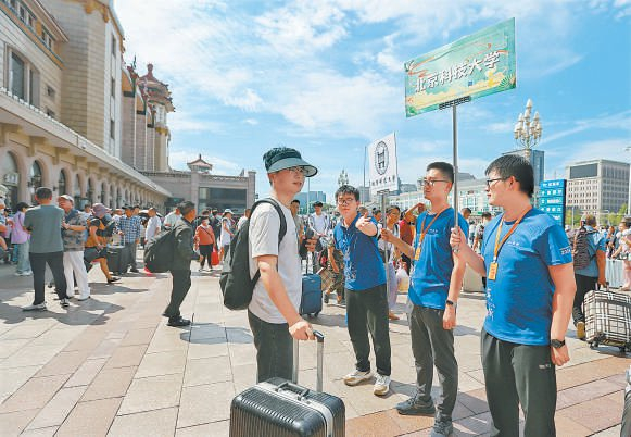 昨天，高校志愿者在北京站出站口迎接新生。 本报记者 潘之望摄