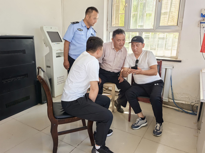 巴某（右一）向民警展示老照片。受访单位供图