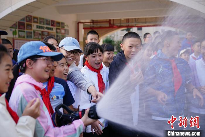 9月4日，云南昆明，学生在消防员指导下操作消防水枪。中新社记者 刘冉阳 摄