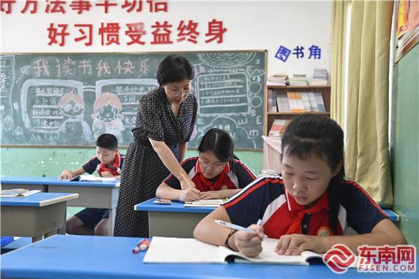 赖丽华利用午休时间，辅导学生作业。