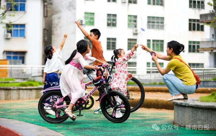 ▲家长和孩子在定南县解放路市民健身休闲广场嬉戏玩耍，乐享亲子时光。