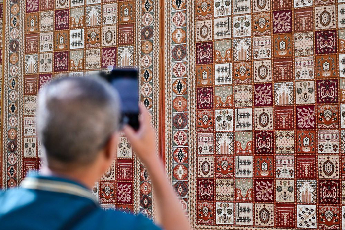   在新疆库车市龟兹小巷，游客拍摄地毯墙。新华社记者 丁磊 摄