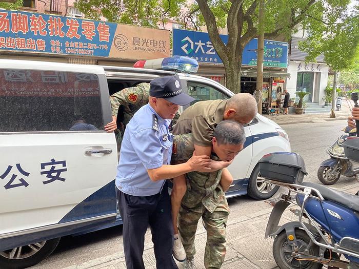 一位年过半百的老伯因脑梗而不能自主站立，民警将他背上警车转移至附近的酒店。澎湃新闻记者 徐祯曜 图