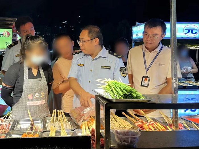 图为执法人员现场向夜宵摊主指出其违法行为。