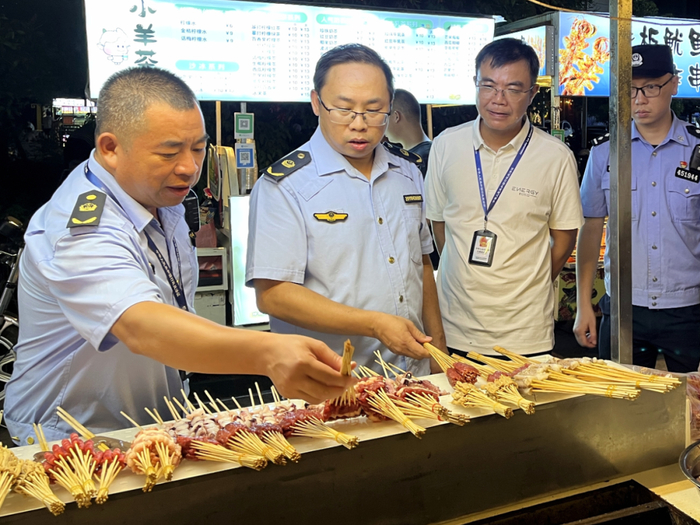 图为执法人员对夜宵摊位上的肉制品进行检查。