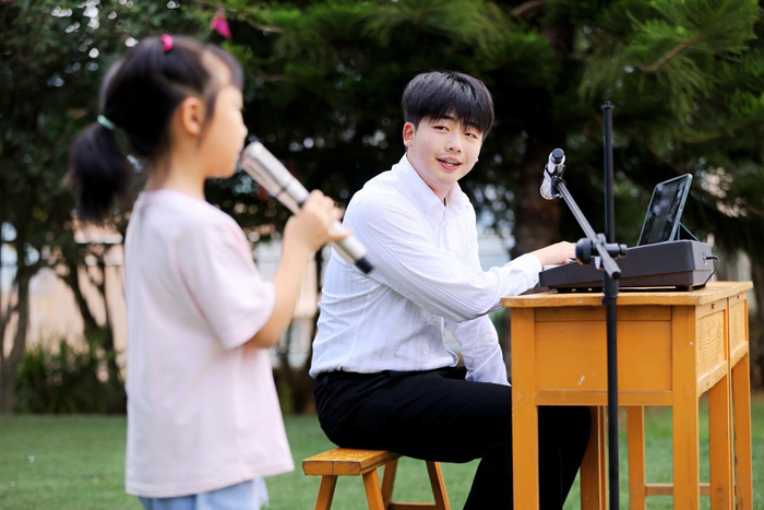 图为贵州师范大学音乐学院志愿者邹奇峰给学生上声乐课