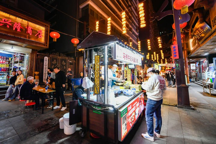 4月28日，游客在兰州市城关区大众巷新光夜市购买特色美食牛奶鸡蛋醪糟。新华每日电讯记者 郎兵兵摄