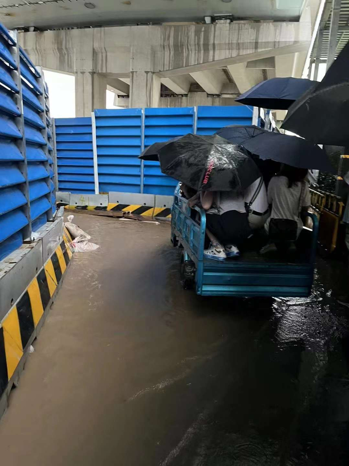 上海地铁9号线金桥站附近，有两位男子开三轮车、铺木板帮人们渡过泥路。 受访者供图