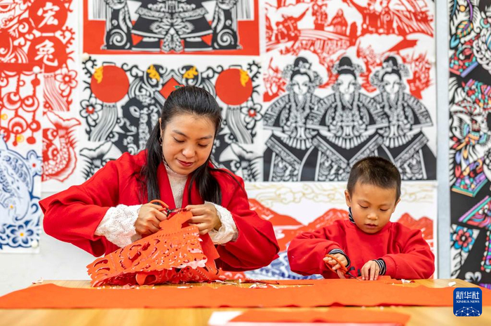 ▲贵州省黔西市文化馆“剪纸迎新年”主题活动上，黔西市剪纸非遗传承人岳红霞（左）带领学生进行剪纸创作。新华社发