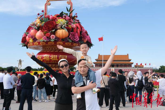 9月25日，北京天安门广场，来自山西晋中的一家三口在“祝福祖国”巨型花篮前拍照。王藜静/摄