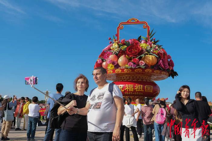 9月25日，北京天安门广场，两名游客在“祝福祖国”巨型花篮前自拍。王藜静/摄