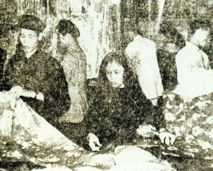 1954年9月，南宁市实行棉布计划供应办法后，对棉布业私商库存的商品进行清理登记。图为市智信棉布店的店员在丈量布匹 