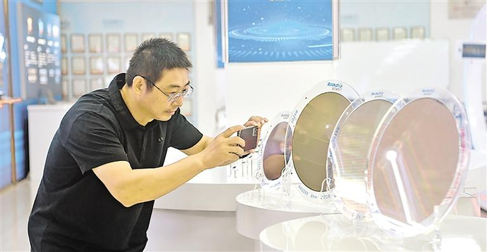参观人员在瑞芯微电子股份有限公司展厅内拍摄8纳米制程晶圆。