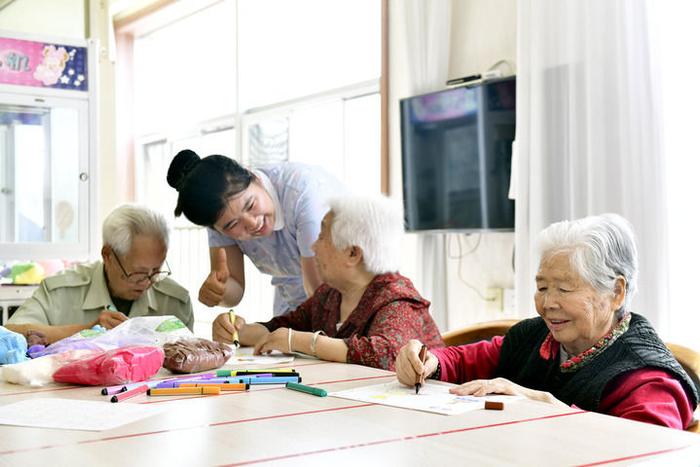 2024年5月25日，在山东省日照市东港区石臼街道日照幸福护理院，老人在工作人员的陪护下做填图游戏。新华社记者 郭绪雷 摄