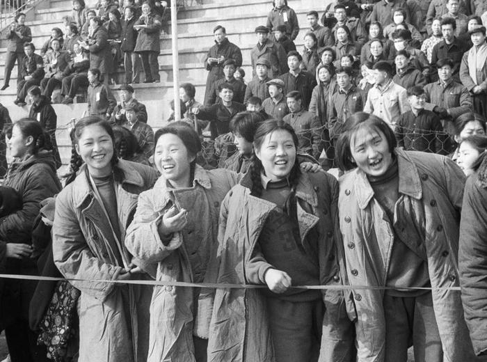 1964年3月8日，北京举行庆祝“三八”杯女子长跑接力比赛，场边身穿军大衣的女青年们观看比赛。新华社记者 黄景达 摄