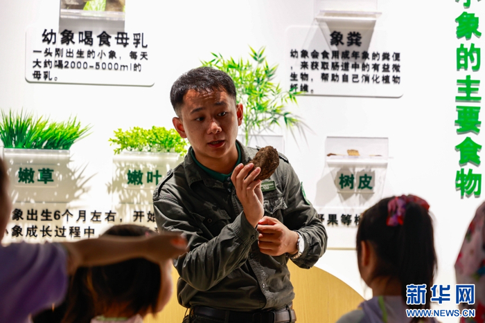 周向国向小朋友们展示象粪样本并介绍相关知识（7月31日摄）。新华网 徐华陵 摄