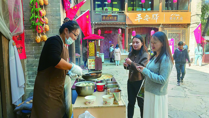 游客在平安驿古镇品尝美食。本报记者 陈 俊 李永皓 摄