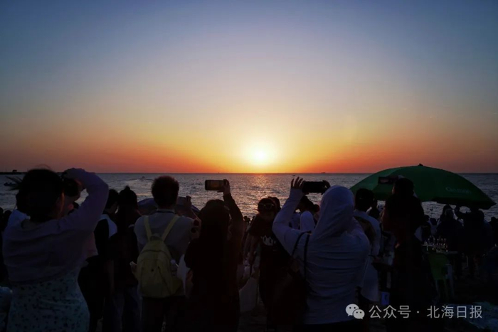 游客们纷纷举起手机相机记录下绝美的日落时刻。郑恩茵 摄