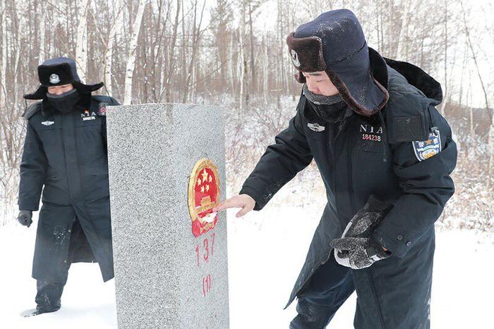 民警徐克宁清理界碑国徽上的积雪。张建鑫 摄