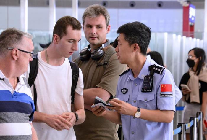 7月10日，北京首都机场边防检查站的民警回答外籍旅客的免签入境问题。（新华社记者 李欣 摄）