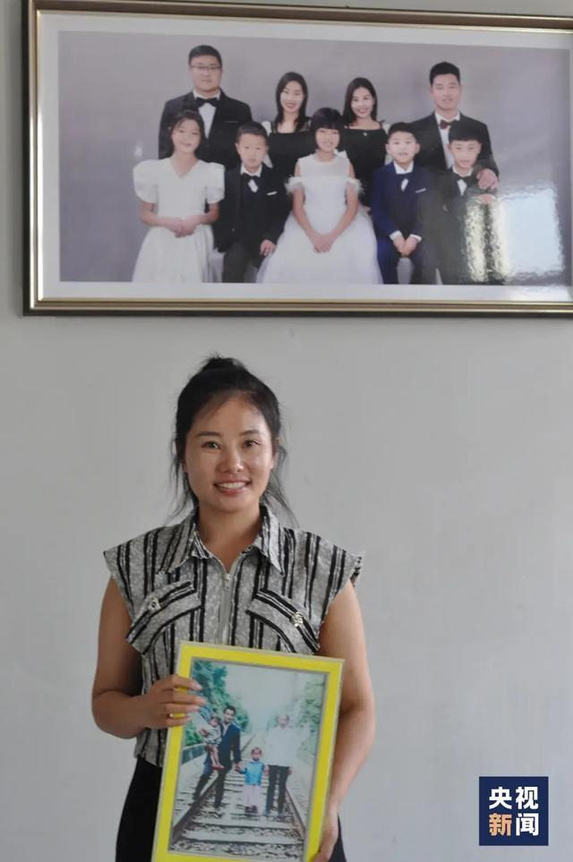 △杨妞花抱着曾经的全家福，身后是与姐姐一家的合照。