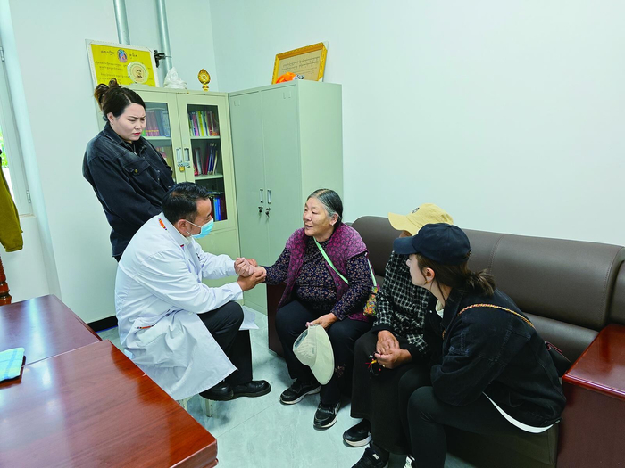 卓保老人在社区工作人员的陪伴下前往医务室检查身体。李兴发 摄