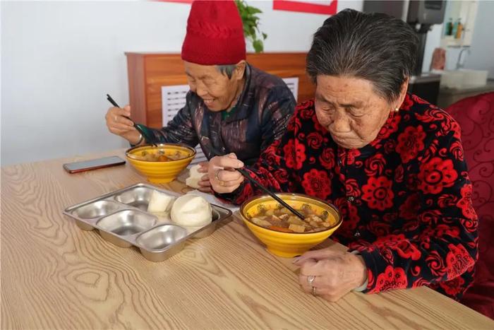 　老人们津津有味地吃着碗里的烩菜。内蒙古日报记者 皇甫美鲜/摄