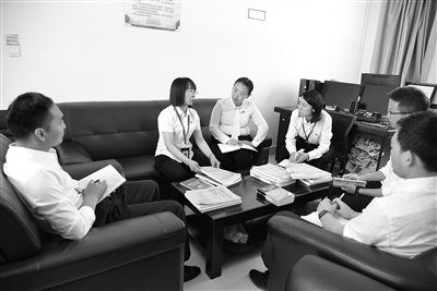 图为李翠萍（左一）正在与同事讨论工作。李东藩 摄