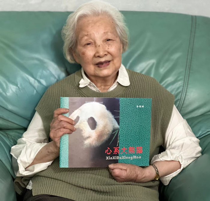 金勖琪捧着自己的摄影作品集《心系大熊猫》合影（2023年12月摄）。（四川省女摄影家协会提供）