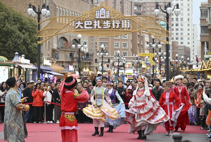 10月16日，与会嘉宾和游客一起在乌鲁木齐大巴扎步行街观看歌舞演出。（图片来源：新华社）