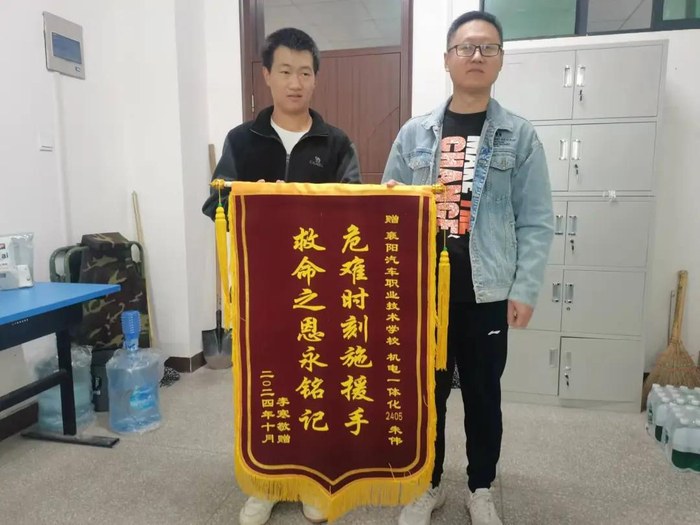 李寒的哥哥李春专程向朱伟（左）送上锦旗。