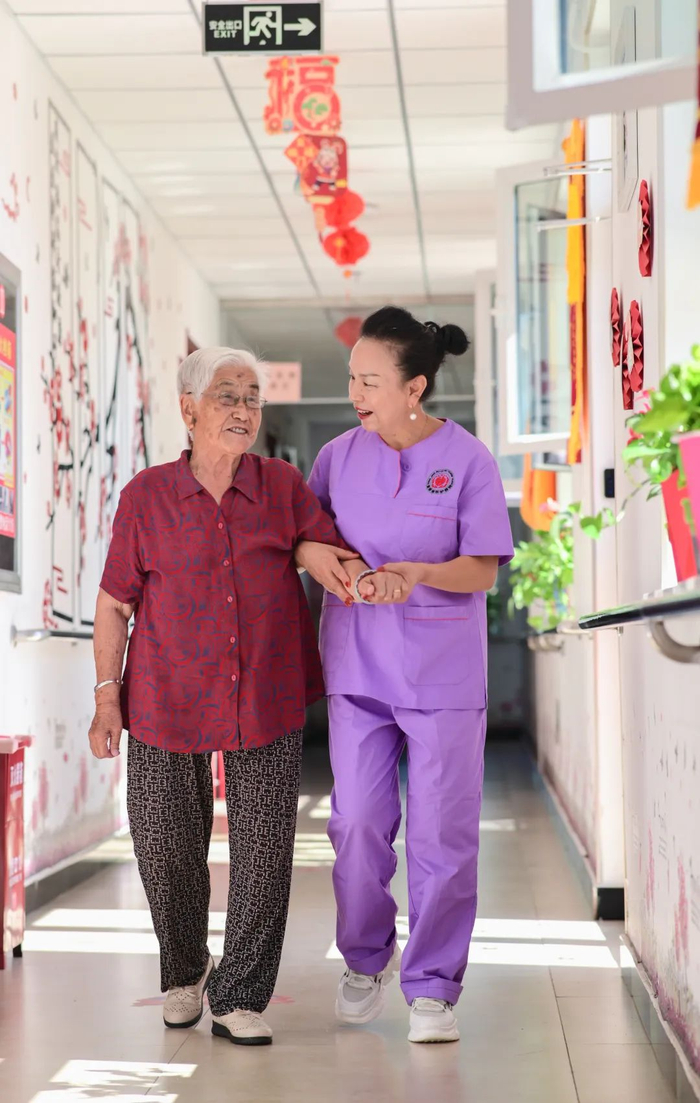 ▲在新疆呼图壁县园户村镇农村幸福大院，工作人员陪老人散步、聊天。供图@视觉中国