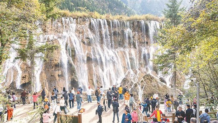 　　在四川省阿坝藏族羌族自治州，九寨沟景区“高颜值”秋景上线。图为近日，游客在景区内欣赏秋季美景。 图片来源：视觉中国