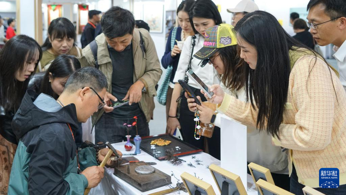 芜湖铁画非遗传承人滕恃勇向观众介绍铁画制作技艺。新华社记者 熊翔鹤 摄